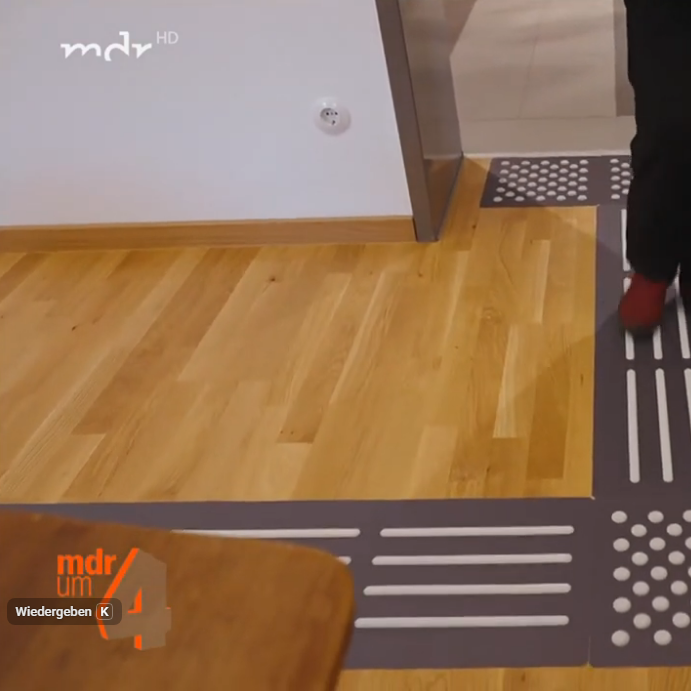Boden mit taktilen Leitlinien und Mustern für Orientierung in einem Raum.
